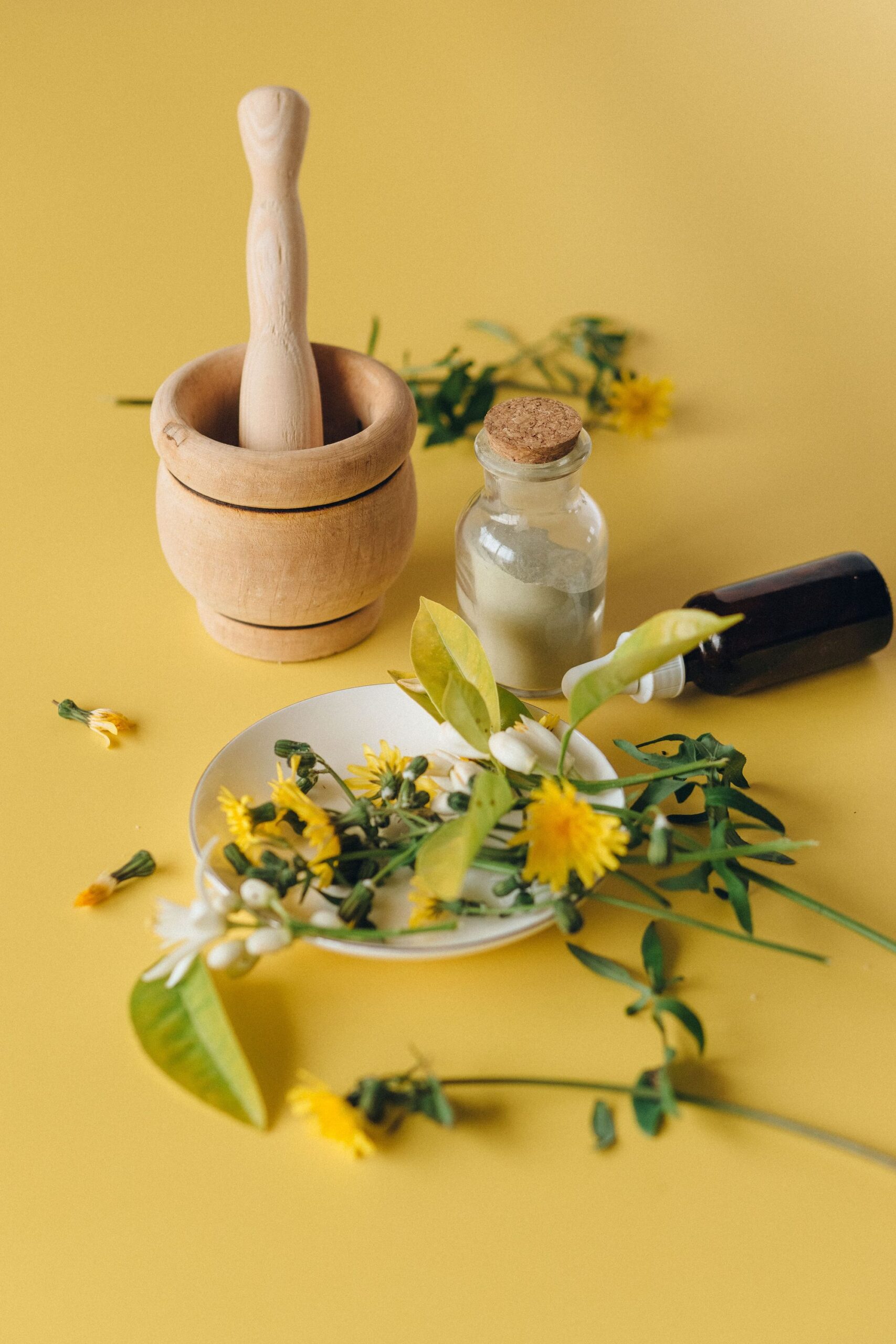 Mortier en bois, fleurs et petits flacons de plantes
