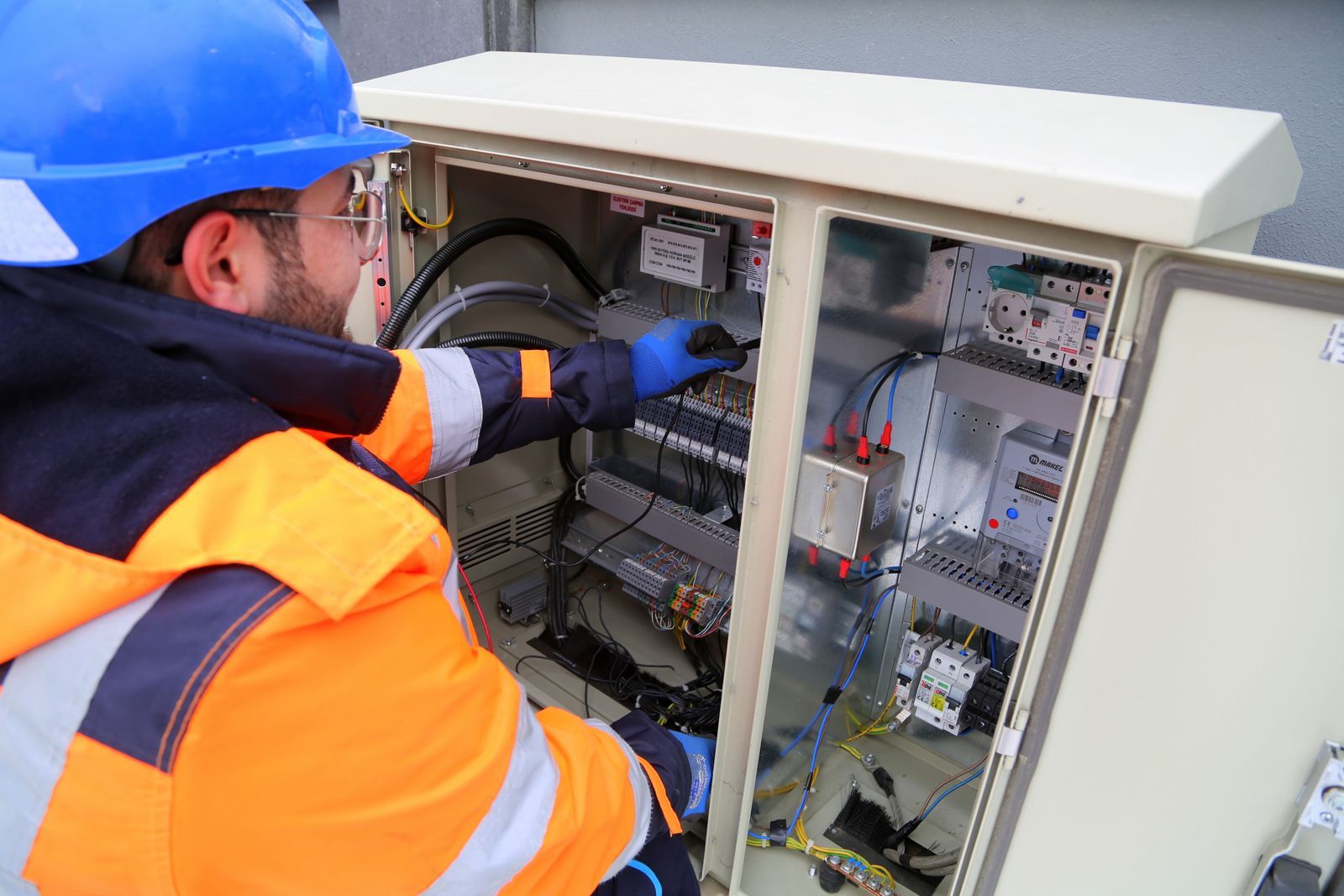 Électricien en casque intervenant sur une armoire électrique